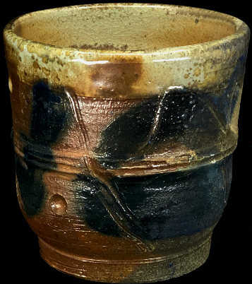 a woodfired cup with a slip and incised line design